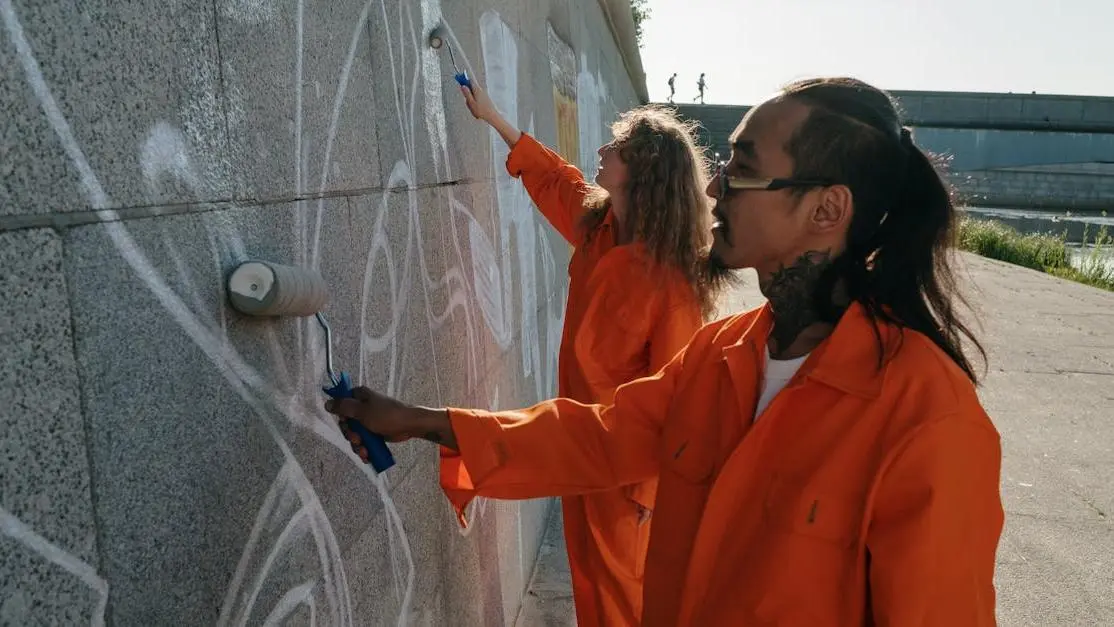 Volunteers in orange uniforms painting over graffiti, demonstrating positive impact volunteering.