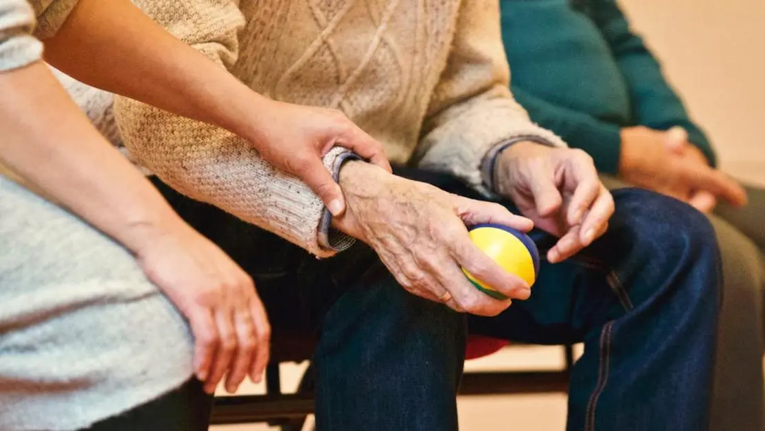 Caregiver holding hands with elderly resident during nursing home volunteer work, showing compassion