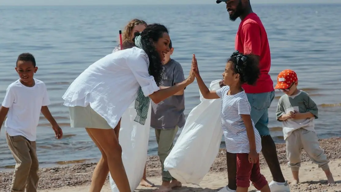 Diverse volunteer organizations cleaning a beach together, adults and children celebrating teamwork
