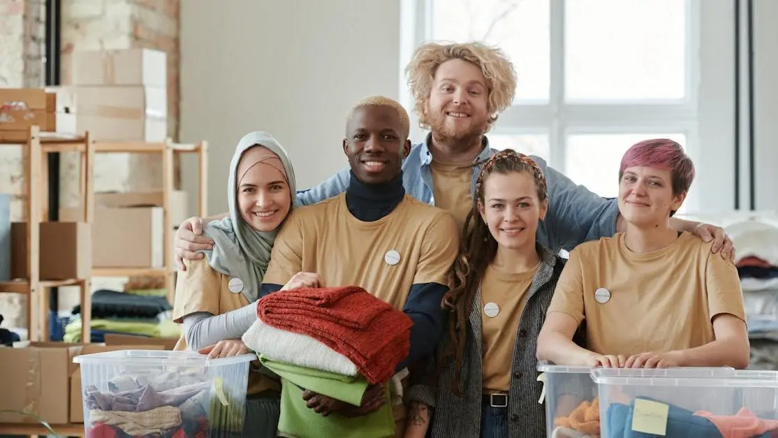 Teens volunteering at a charity center, sorting clothes as part of a community service project.