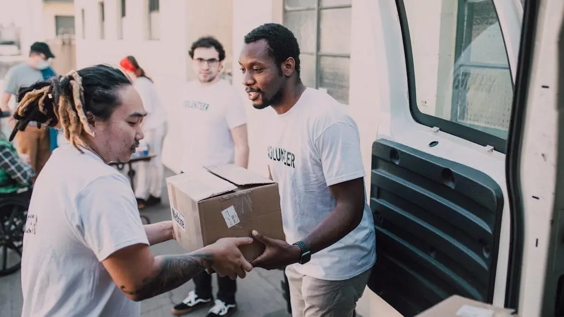 Group doing free volunteer work abroad, unloading donated supplies from a van to help locals