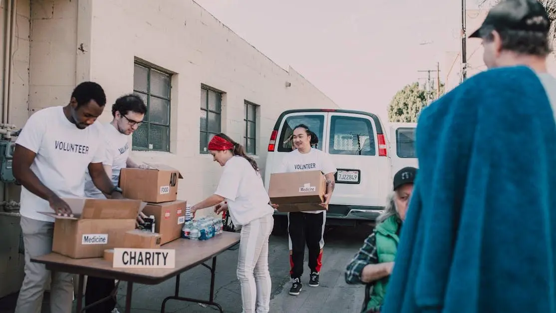 Diverse group of people doing traveling volunteer work, organizing donations outdoors together.