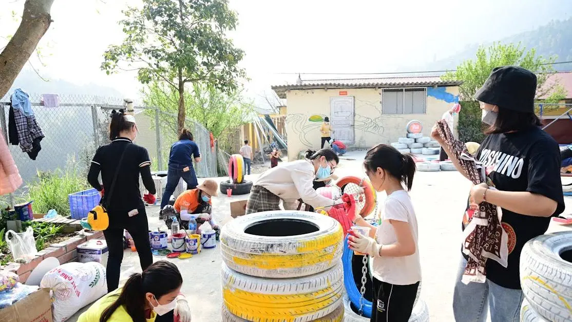 Volunteers painting tires together at a community volunteer event outdoors