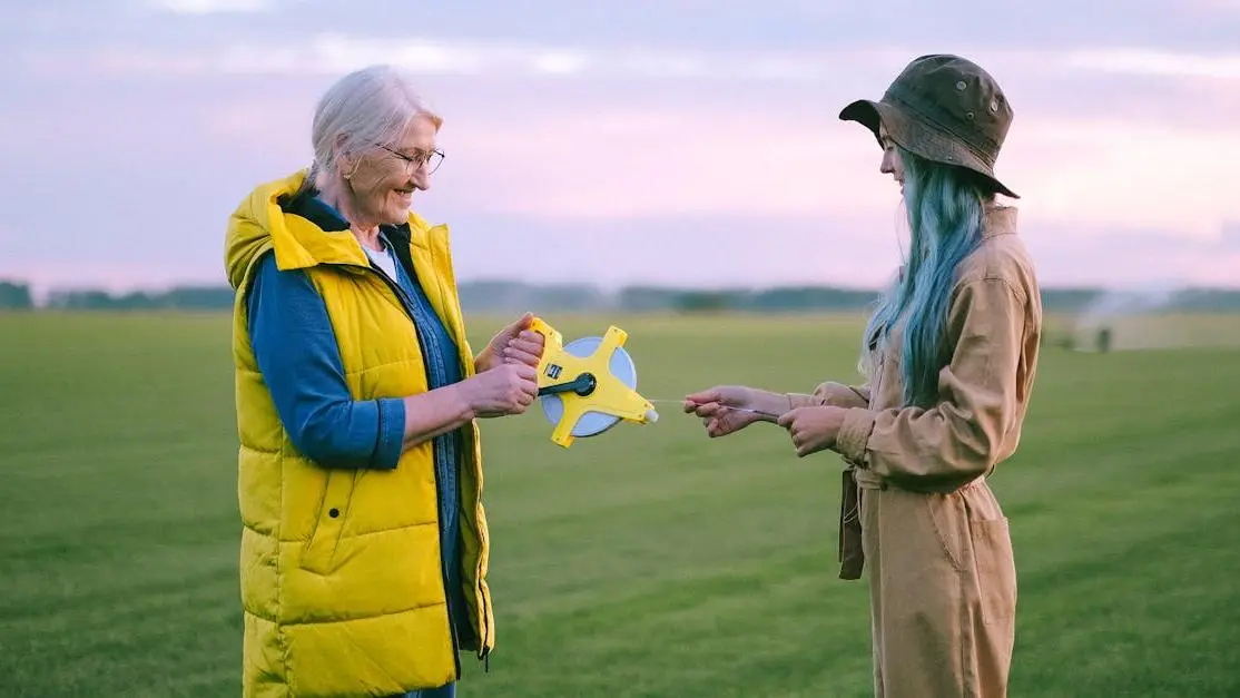 Elderly and young woman measuring land at sunset, volunteering abroad for volunteer work overseas