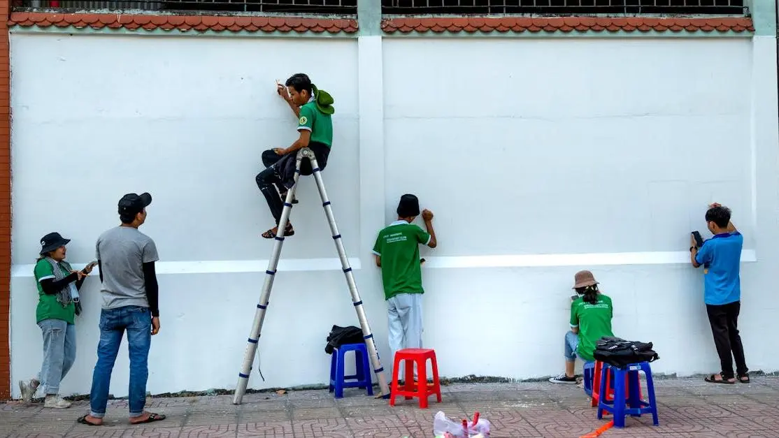 Teens painting a colorful outdoor mural, showcasing creative teamwork and youth volunteering