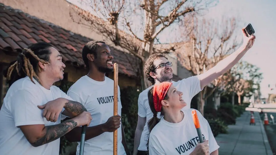 Smiling diverse family volunteer opportunities group in white shirts taking an outdoor selfie