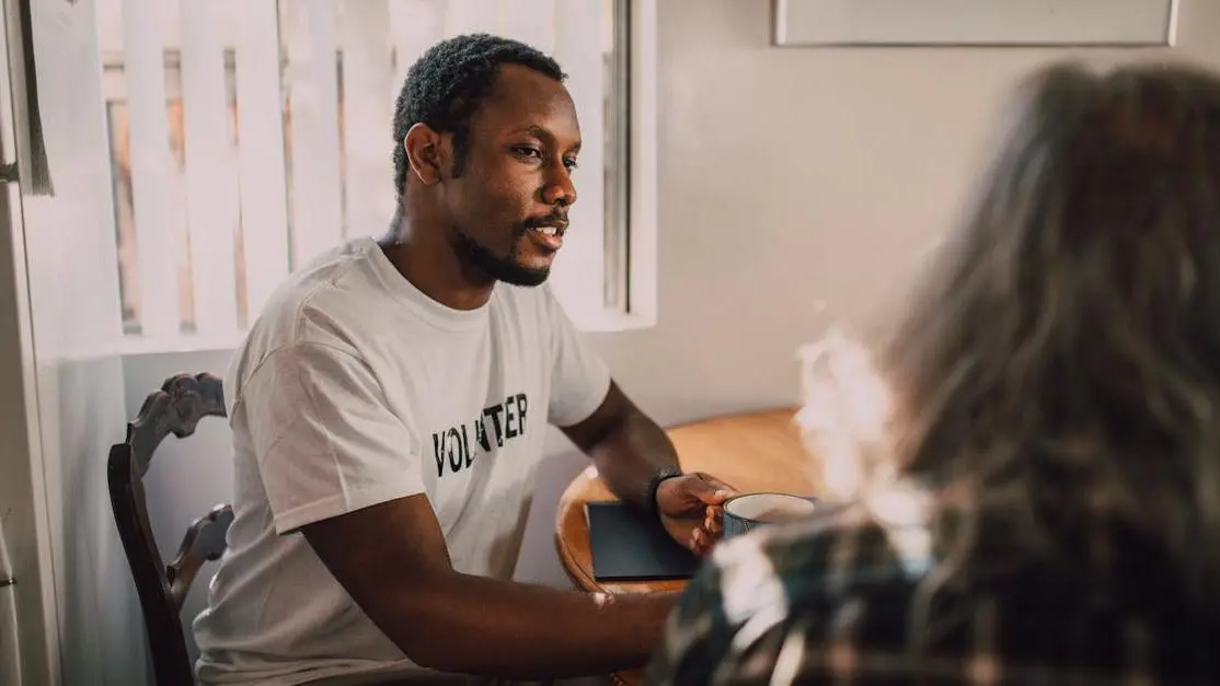 Psychology volunteer facilitating a thoughtful conversation in a bright, welcoming room